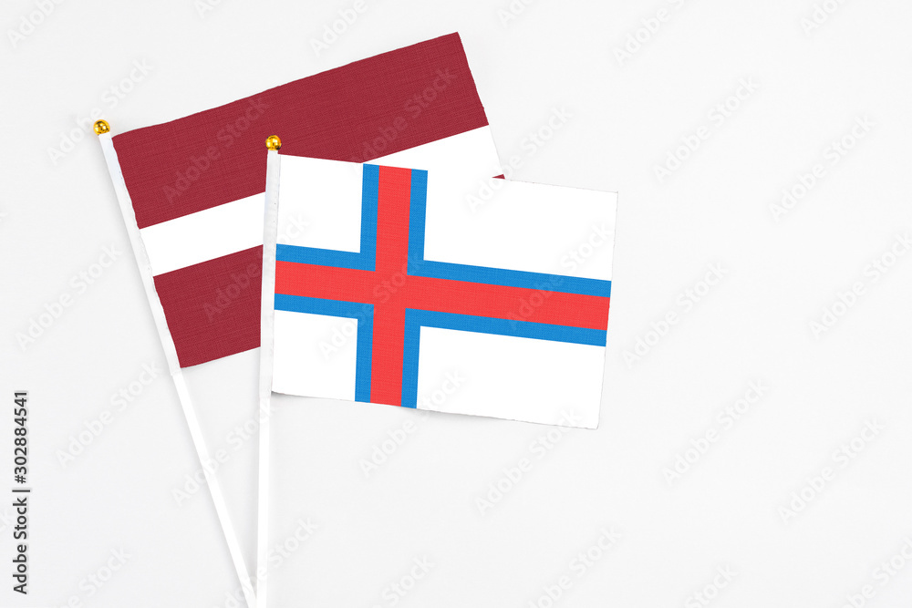 Faroe Islands and Latvia stick flags on white background. High quality fabric, miniature national flag. Peaceful global concept.White floor for copy space.
