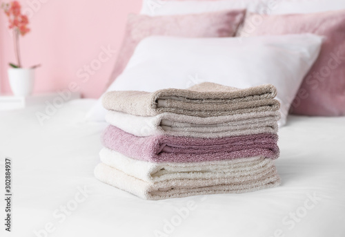 Stack of soft clean towels on bed