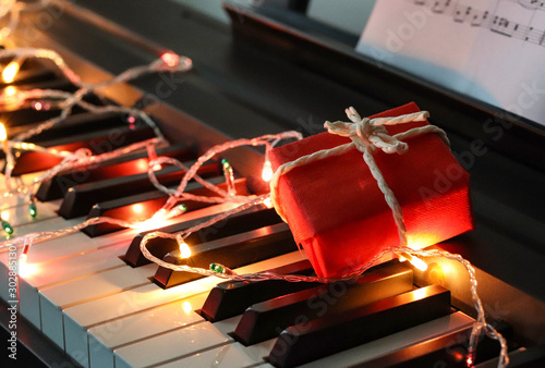 Wall Mural Red gift box with string lights glowing on piano keyboard.