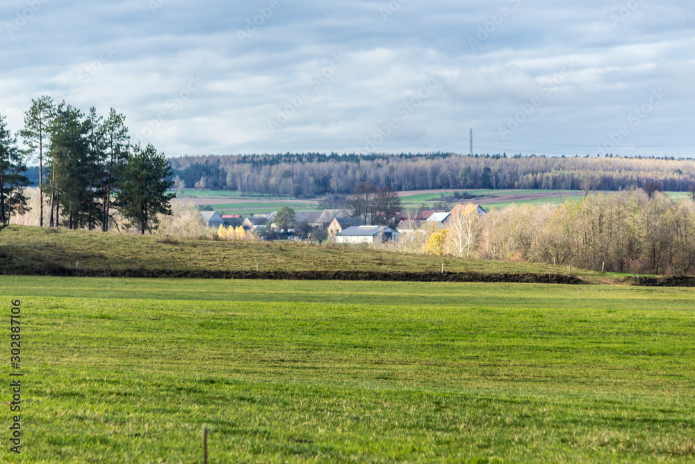 A village among fields and pastures. Green meadow in the foreground. Late autumn in Podlasie, Poland.