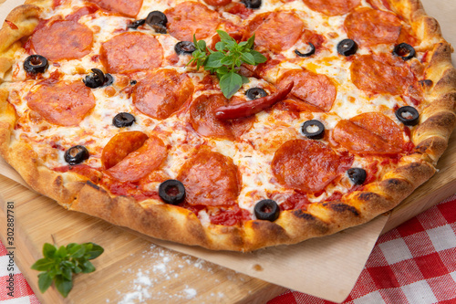 Pepperoni pizza close-up with various ingredients decorated with Basil, an assortment of traditional Italian fast food