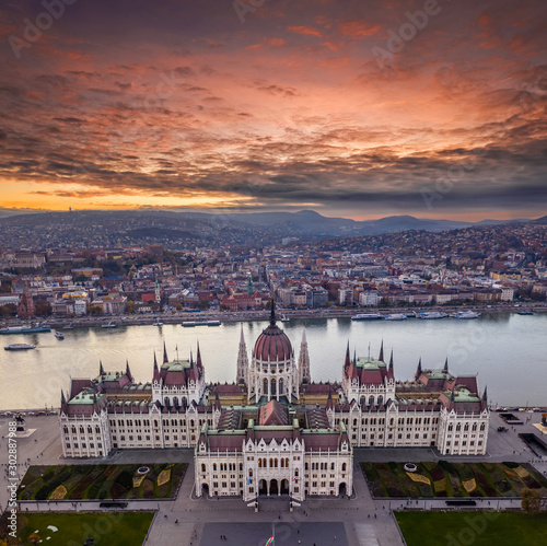 Budapest  Hungary - Aerial drone view of the beautiful Parliament of Hungary with a dramatic colorful sunset and sightseeing boats on River Danube at autumn. Buda side and Buda Hills at background