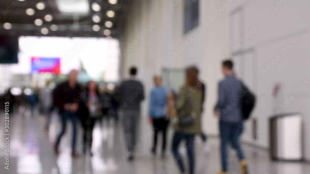 Blurred crowd of people passing by in a conference hallway Blurred crowd of people passing by in a conference hallway