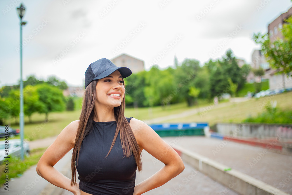 Young slim woman with a sporty body, long hair, dressed in a sports top and leggings, prepares for a morning jog in the park. Beautiful healthy girl wearing sportswear doing exercises in the park