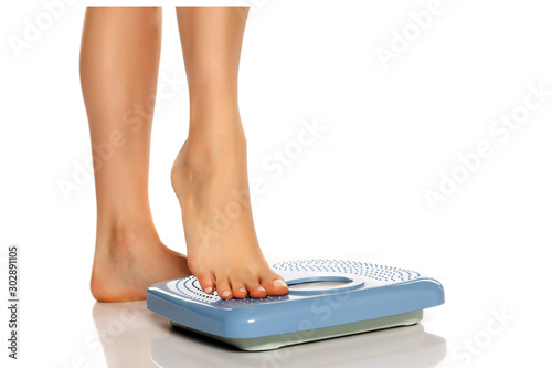 Pretty female legs on scales on white background
