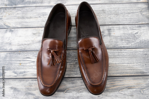 Brown classic loafers with tassels stand on a wooden stand