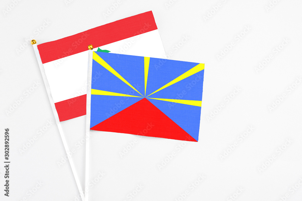 Naklejka premium Reunion and Lebanon stick flags on white background. High quality fabric, miniature national flag. Peaceful global concept.White floor for copy space.