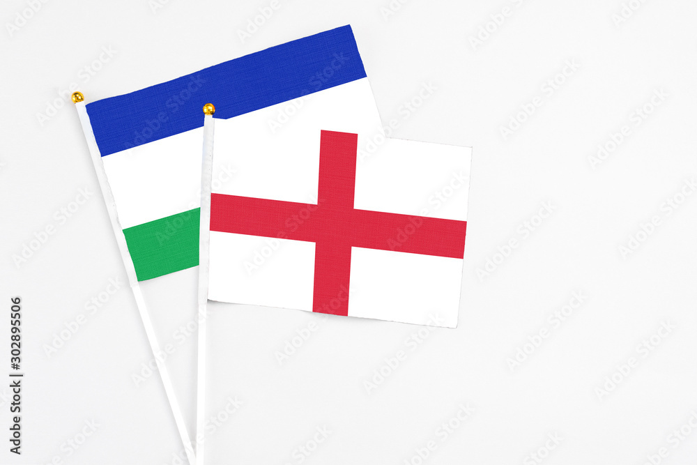 England and Lesotho stick flags on white background. High quality fabric, miniature national flag. Peaceful global concept.White floor for copy space.