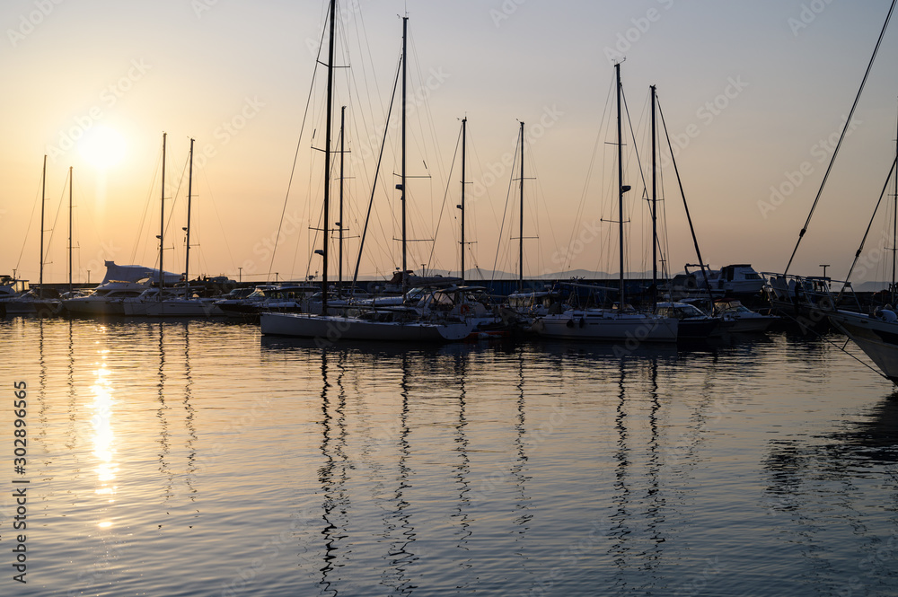 Yachts and boats reflected in water at the sunset - marina view.
