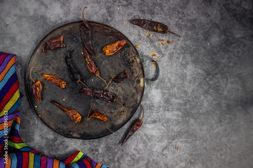 Dry chillis in a comal or hotplate for being roasted with a mexican fabric aside