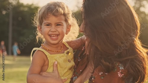 Pleased indian woman enjoys the moment with her happy child girl and whirling her in park outdoors