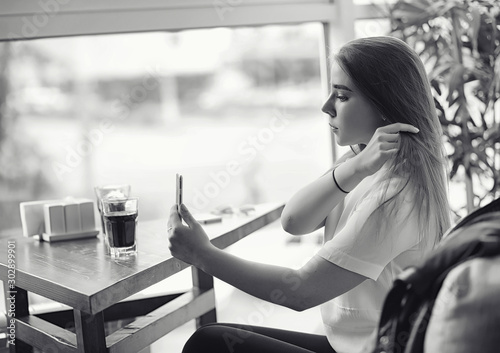 Young girl in a cafe. The girl is sitting on the couch and talking on the phone.