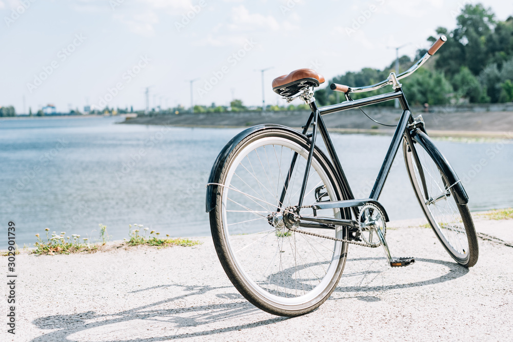 Fototapeta premium bicycle near blue river in summer in sunshine
