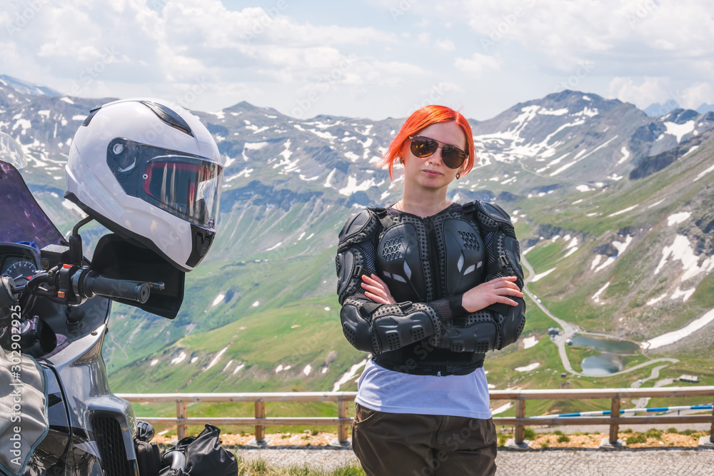 Girl in full biker outfit, jacket protection turtle. Touring motorcycle  with big bags. The snowy peaks of the Alpine mountains on background.  Grossglockner Pass. Austria, Italy Stock Photo | Adobe Stock