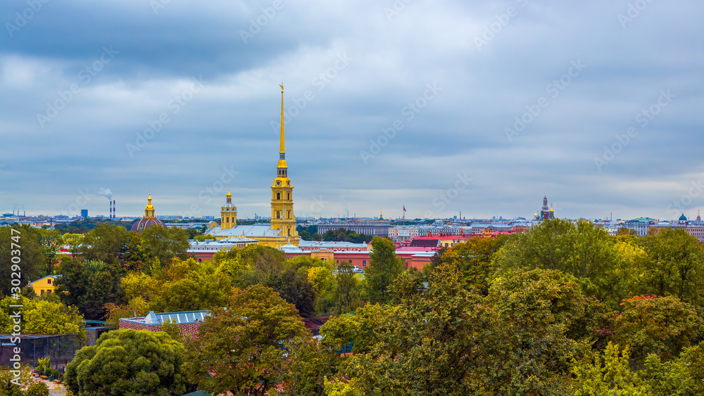 Fototapeta premium Beautiful panorama of the historic city center of St. Petersburg, Russia. Top view of the Peter and Paul Fortress and the cathedral with a golden spire. In the foreground is Alexander Park.