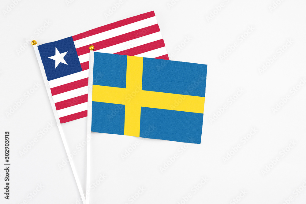 Sweden and Liberia stick flags on white background. High quality fabric, miniature national flag. Peaceful global concept.White floor for copy space.