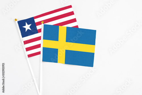 Sweden and Liberia stick flags on white background. High quality fabric, miniature national flag. Peaceful global concept.White floor for copy space. photo