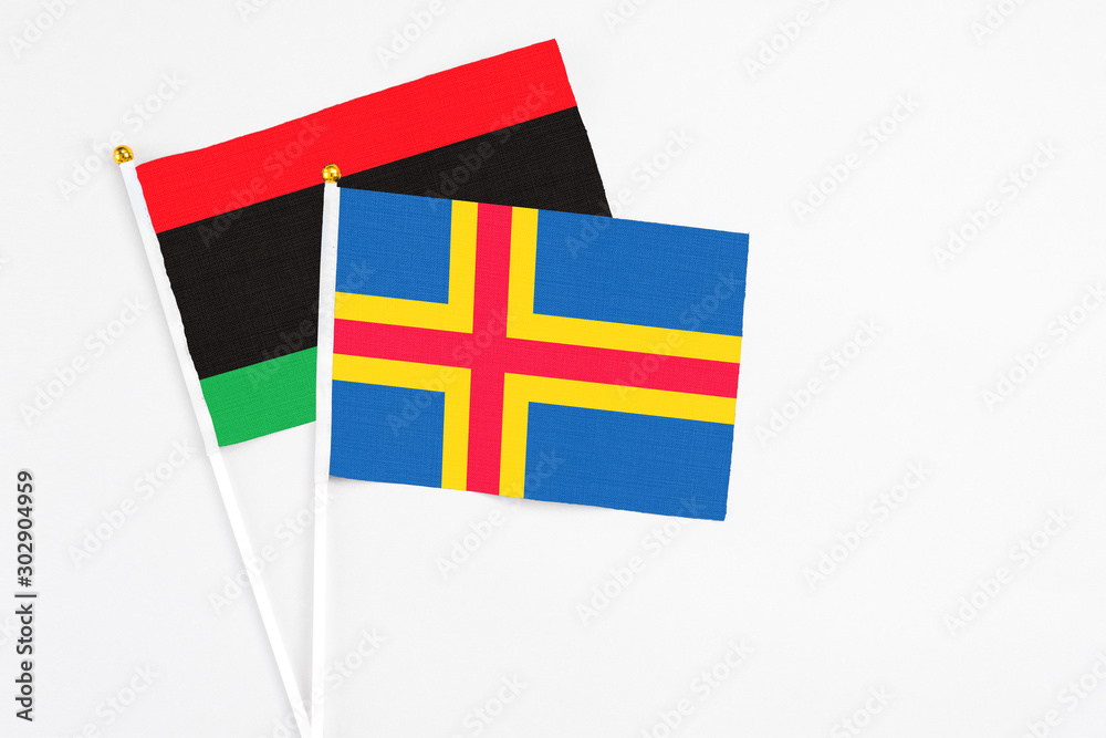 Aland Islands and Libya stick flags on white background. High quality fabric, miniature national flag. Peaceful global concept.White floor for copy space. Aland Islands and Libya stick flags on white background. High quality fabric, miniature national flag. Peaceful global concept.White floor for copy space.