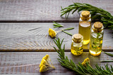 Aromatherapy. Essential oils in small bottles near fresh herbs on dark wooden background copy space