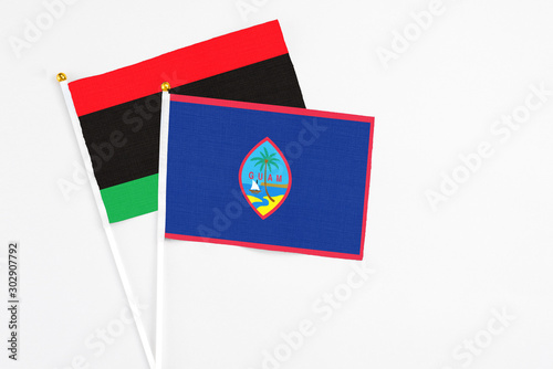 Guam and Libya stick flags on white background. High quality fabric  miniature national flag. Peaceful global concept.White floor for copy space.