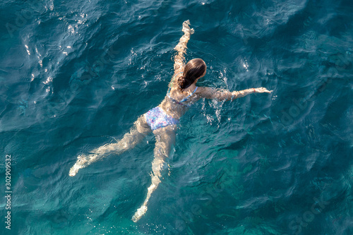 A girl swims in the blue water of the sea