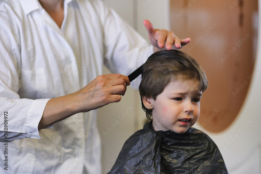 Hairdresser and boy. The boy is doing his hair. Cut hair child in the hairdresser.