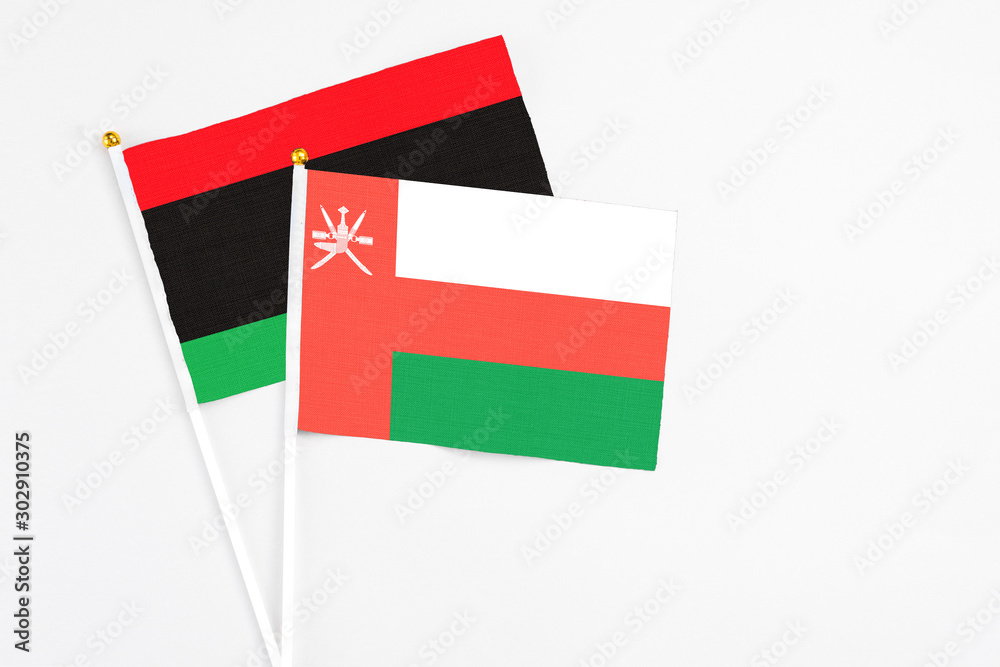 Oman and Libya stick flags on white background. High quality fabric, miniature national flag. Peaceful global concept.White floor for copy space. Oman and Libya stick flags on white background. High quality fabric, miniature national flag. Peaceful global concept.White floor for copy space.