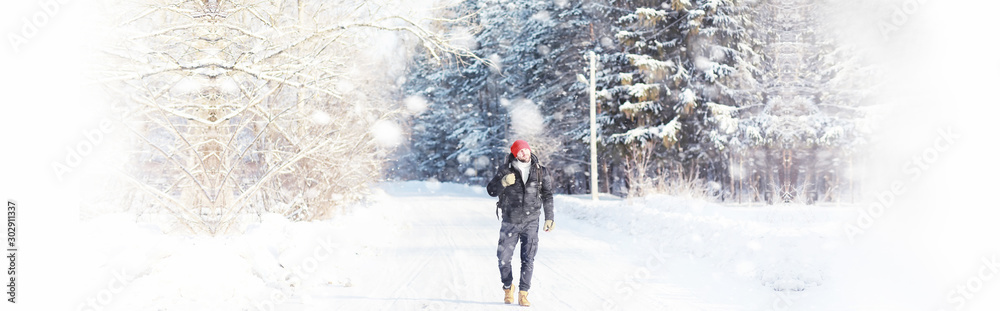 A man travels with a backpack. Winter hike in the forest. Tourist on a walk in the winter in the park.