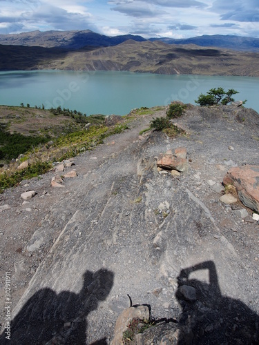 Shadows on the ground and a beautiful colored lake visible in the distance  Torres del Paine trekking  Torres del Paine National Park  Patagonia  Chile