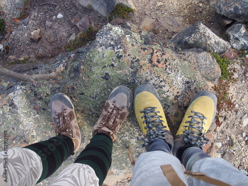The feet of a couple of climber standing on a rock, surrounded by majestic mountains, Torres del Paine trekking, Torres del Paine National Park, Patagonia, Chile