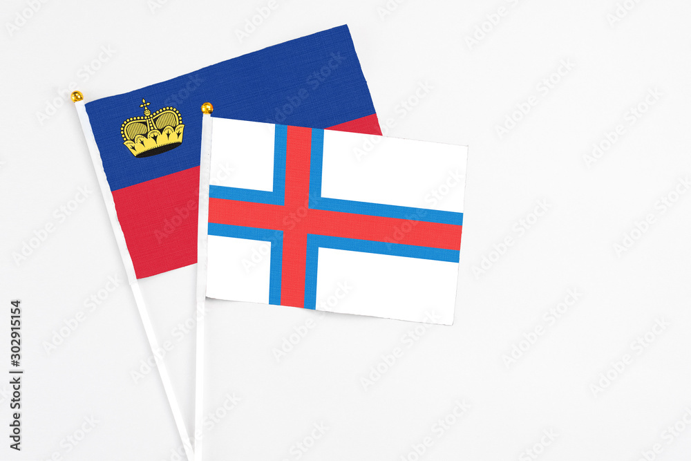 Faroe Islands and Liechtenstein stick flags on white background. High quality fabric, miniature national flag. Peaceful global concept.White floor for copy space.
