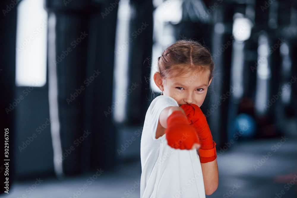 Portrait of young little girl in sportive wear that is in the gym have exercise day. Conception of boxing Portrait of young little girl in sportive wear that is in the gym have exercise day. Conception of boxing