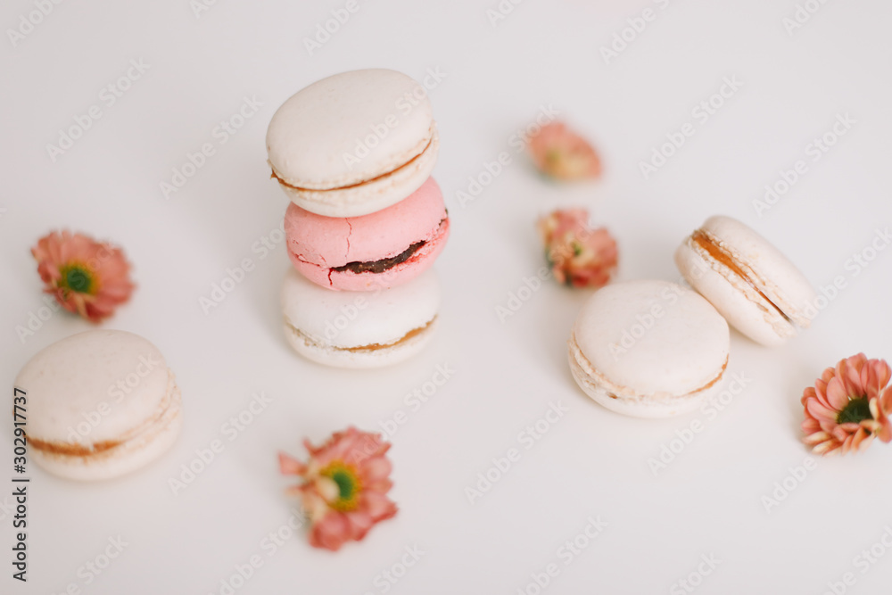 Tasty macarons cookies and flowers on white background. Colorful french desserts. March 8, Spring  background. Valentines, Women, Mothers day concept. Copy space, minimal style, flat lay, top view.