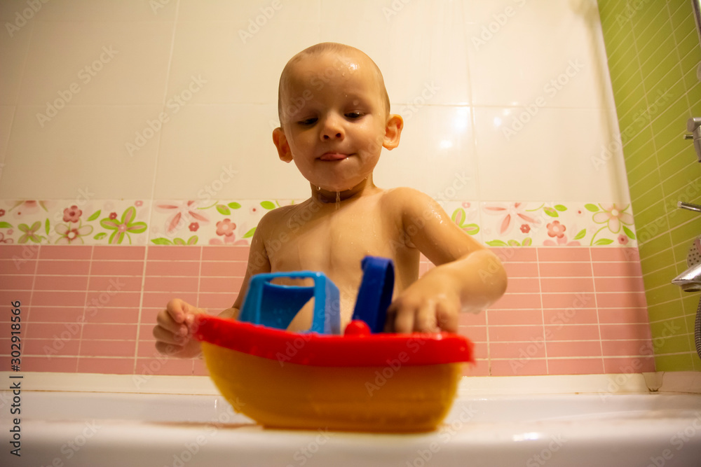 Happy little boy in the bathroom playing with plastic toy boat. Infant training and bathing. Hygiene and care for young children. Happy little boy in the bathroom playing with plastic toy boat. Infant training and bathing. Hygiene and care for young children.