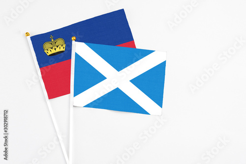 Scotland and Liechtenstein stick flags on white background. High quality fabric, miniature national flag. Peaceful global concept.White floor for copy space.