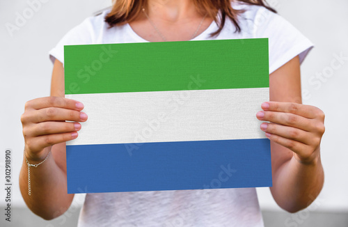 woman holds flag of Sierra Leone on paper sheet