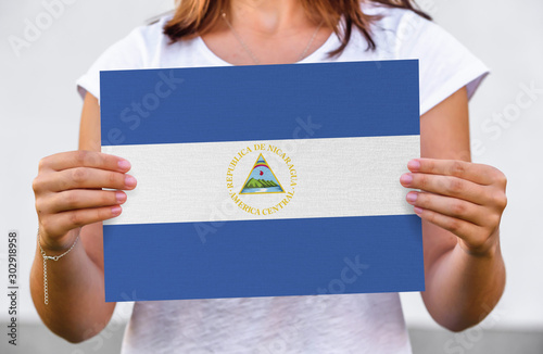 woman holds flag of Nicaragua on paper sheet