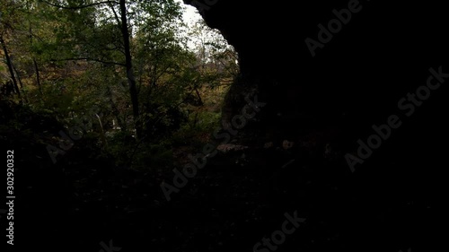 Forward moving in dark cave under rocky cliff, reveal of flooded river photo