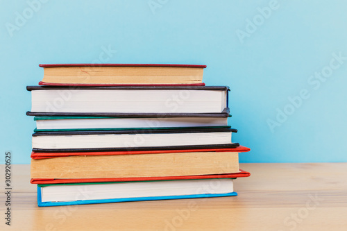 A simple composition of many hardback books  raw books on a wooden table and a bright blue background