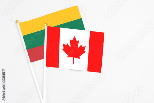 Canada and Lithuania stick flags on white background. High quality fabric, miniature national flag. Peaceful global concept.White floor for copy space.