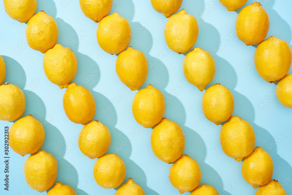 pattern of ripe yellow lemons on blue background with shadows