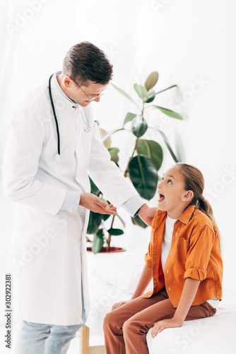 smiling pediatrist in white coat and child in clinic