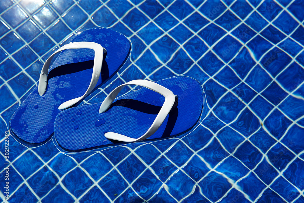 Blue flip flops floating in swimming pool Blue flip flops floating in swimming pool