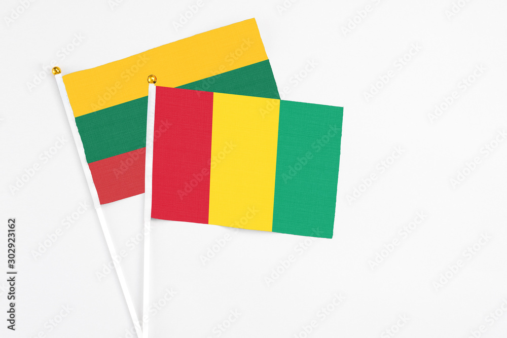 Fototapeta premium Guinea and Lithuania stick flags on white background. High quality fabric, miniature national flag. Peaceful global concept.White floor for copy space.