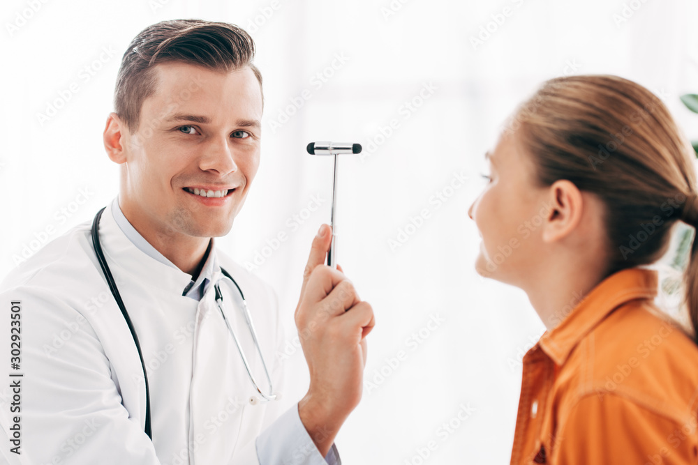 child and smiling pediatrist in white coat holding reflex hammer child and smiling pediatrist in white coat holding reflex hammer