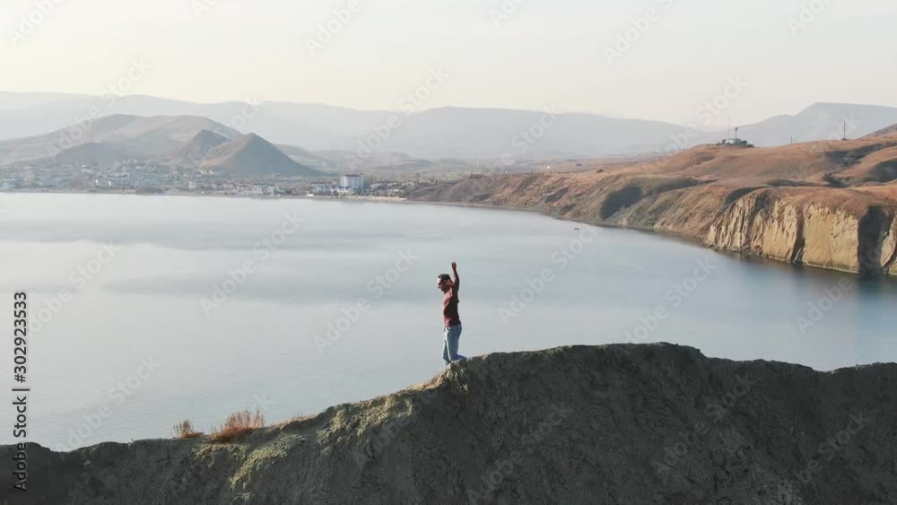 A man does morning sport exercises on a hill against the background of the sea. A man does morning sport exercises on a hill against the background of the sea.