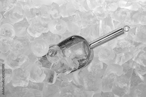 Close up stainless ice scoop with ice cubes in bucket top view use for food and beverage background