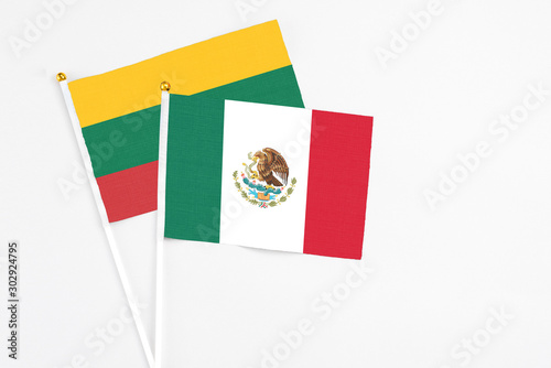 Mexico and Lithuania stick flags on white background. High quality fabric, miniature national flag. Peaceful global concept.White floor for copy space.