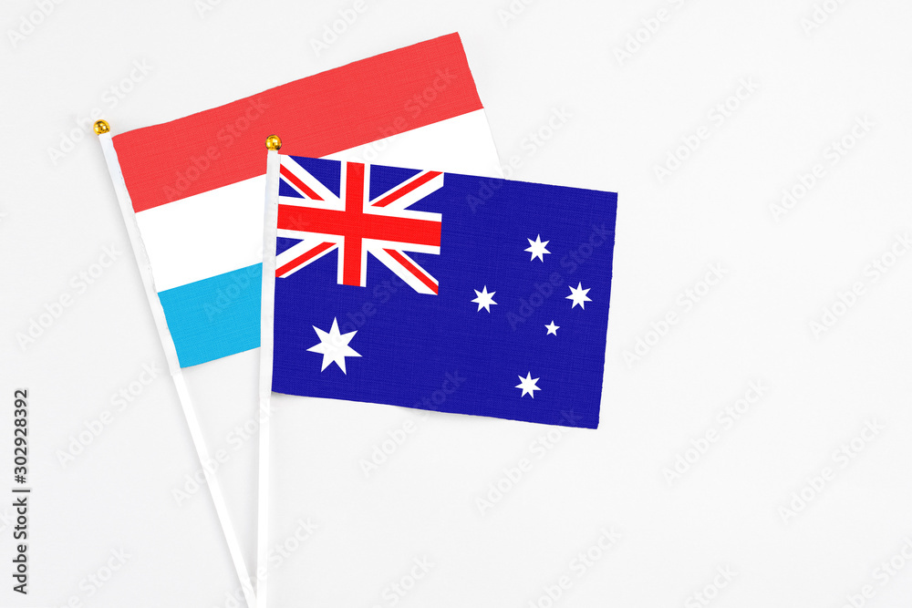 Fototapeta premium Australia and Luxembourg stick flags on white background. High quality fabric, miniature national flag. Peaceful global concept.White floor for copy space.