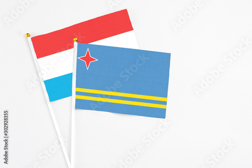 Aruba and Luxembourg stick flags on white background. High quality fabric  miniature national flag. Peaceful global concept.White floor for copy space.